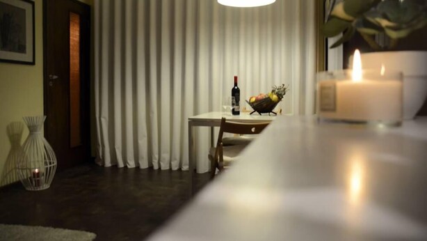 Une pièce avec une table à manger, une bougie et un panier de fruits.