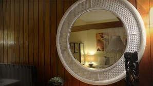 Un miroir rond, doté d’un cadre texturé, fixé sur un mur en bois.