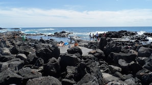 Ein felsiger Strand mit Menschen und Wellen.