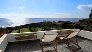 Eine Dachterrasse mit Meerblick, einer Hängematte und Pflanzenkübeln.