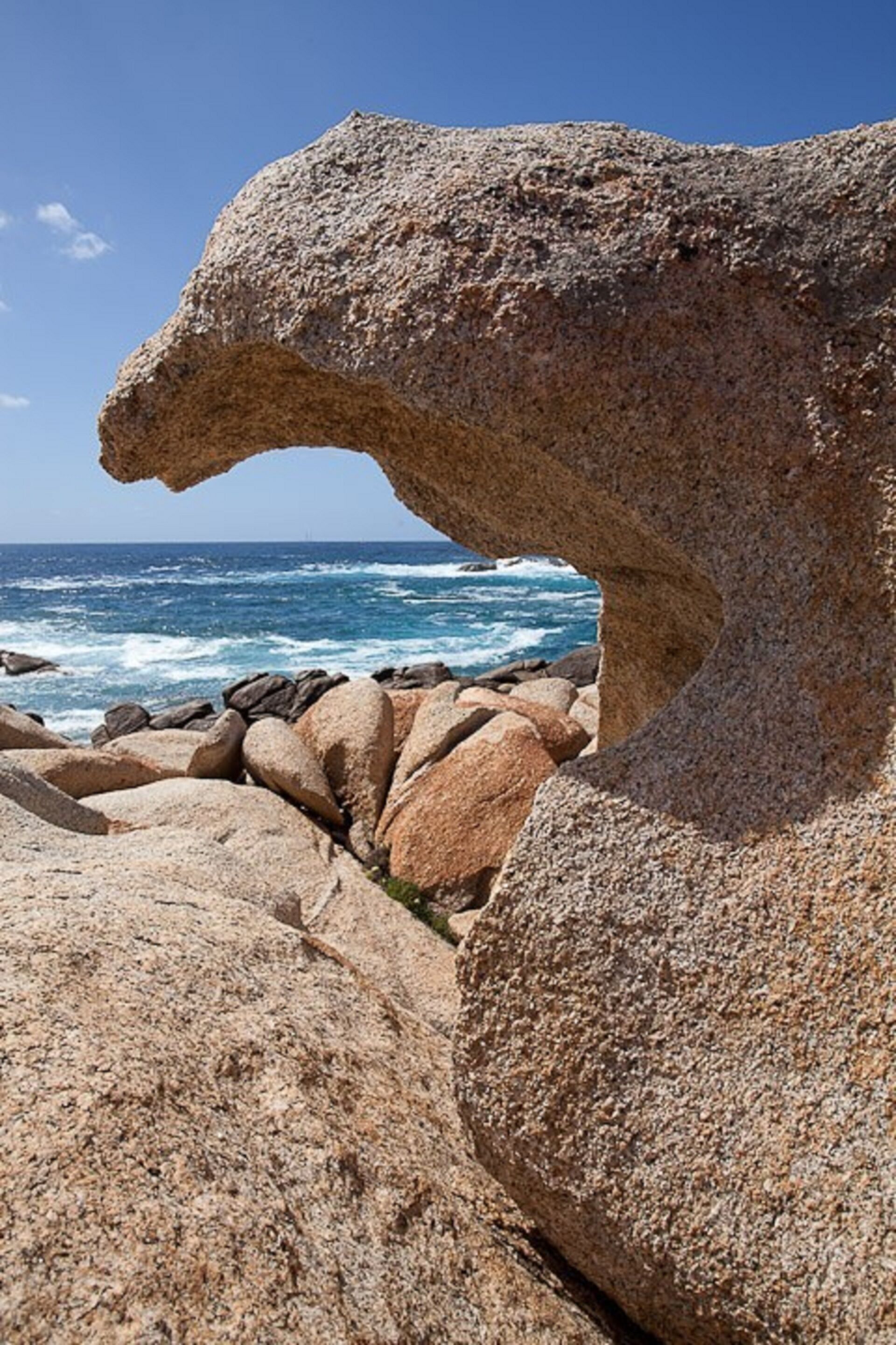 A large rock formation with a natural archway overlooking the ocean.