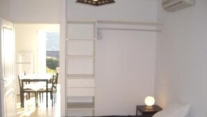 A bedroom with a bed, a nightstand, a desk, and a chair. There is a window with daylight coming through.