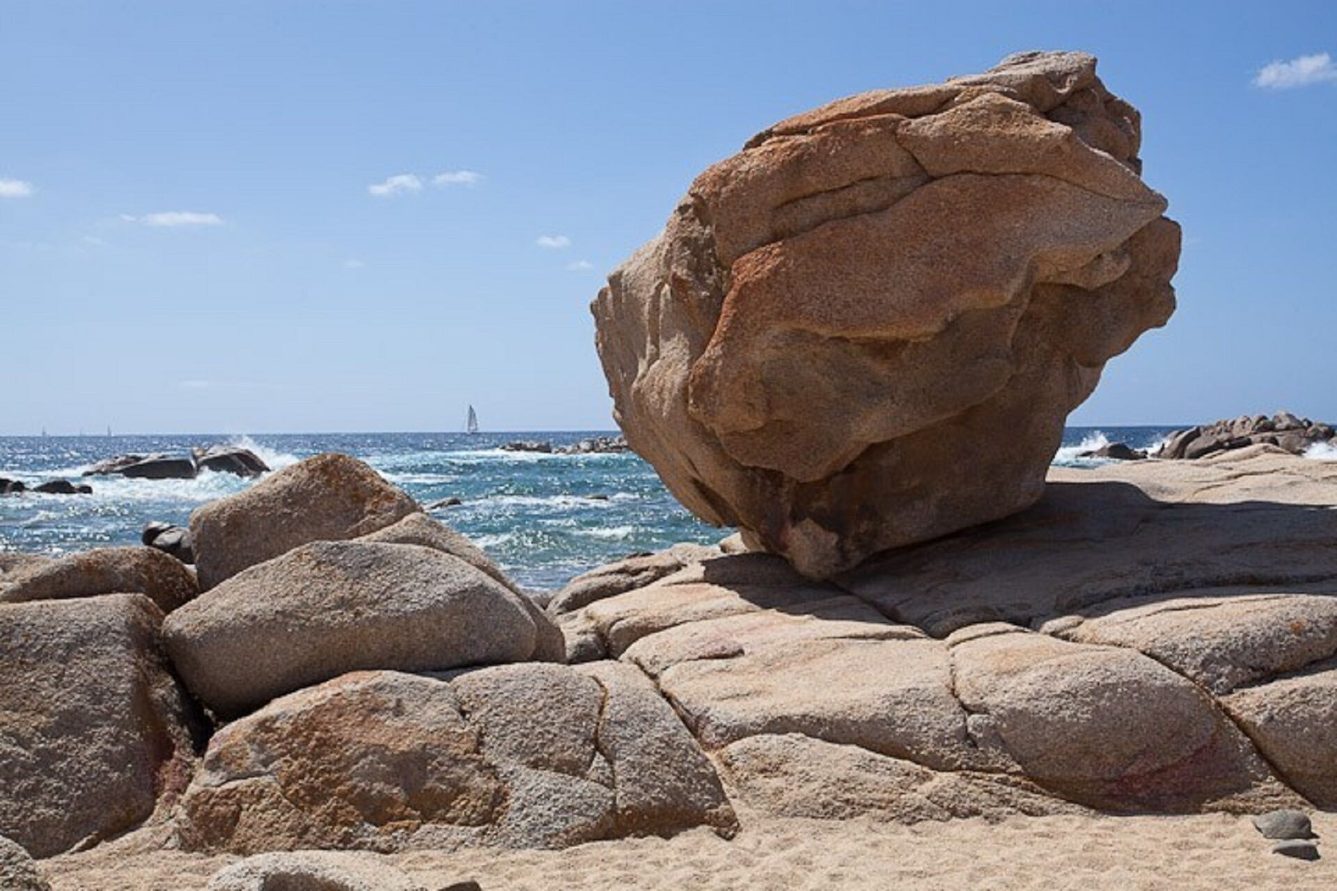 A rocky beach with large boulders and the ocean in the background.