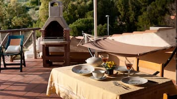 Un espacio de comedor al aire libre con una mesa dispuesta para dos, una parrilla y una hamaca.