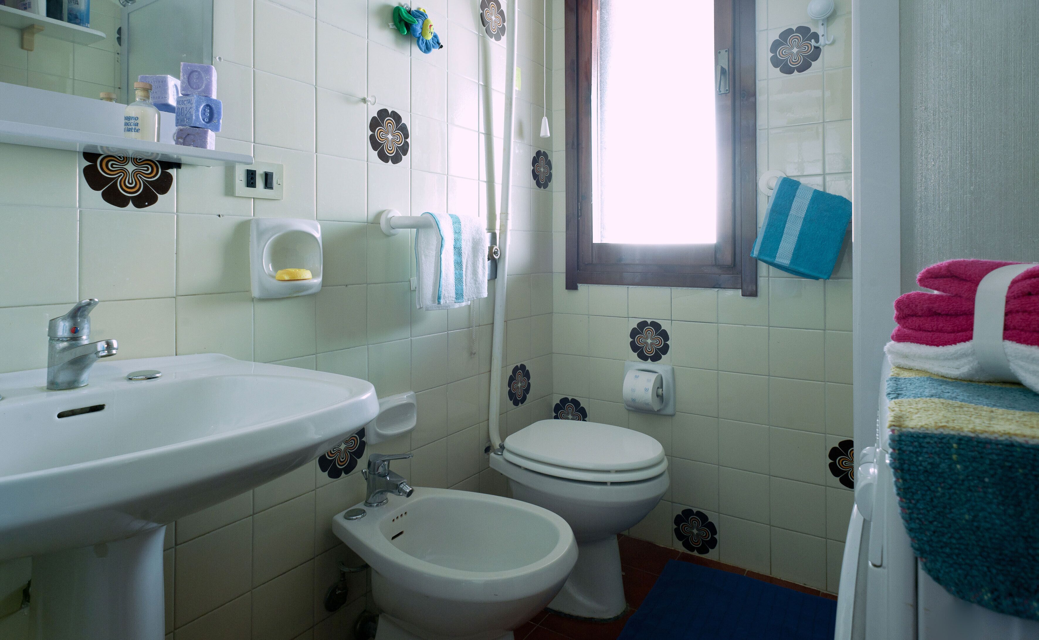 Un baño con lavamanos, inodoro, bidé y ventana.