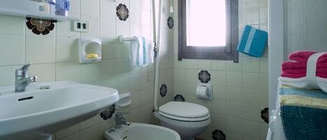 Un baño con lavamanos, inodoro, bidé y ventana.