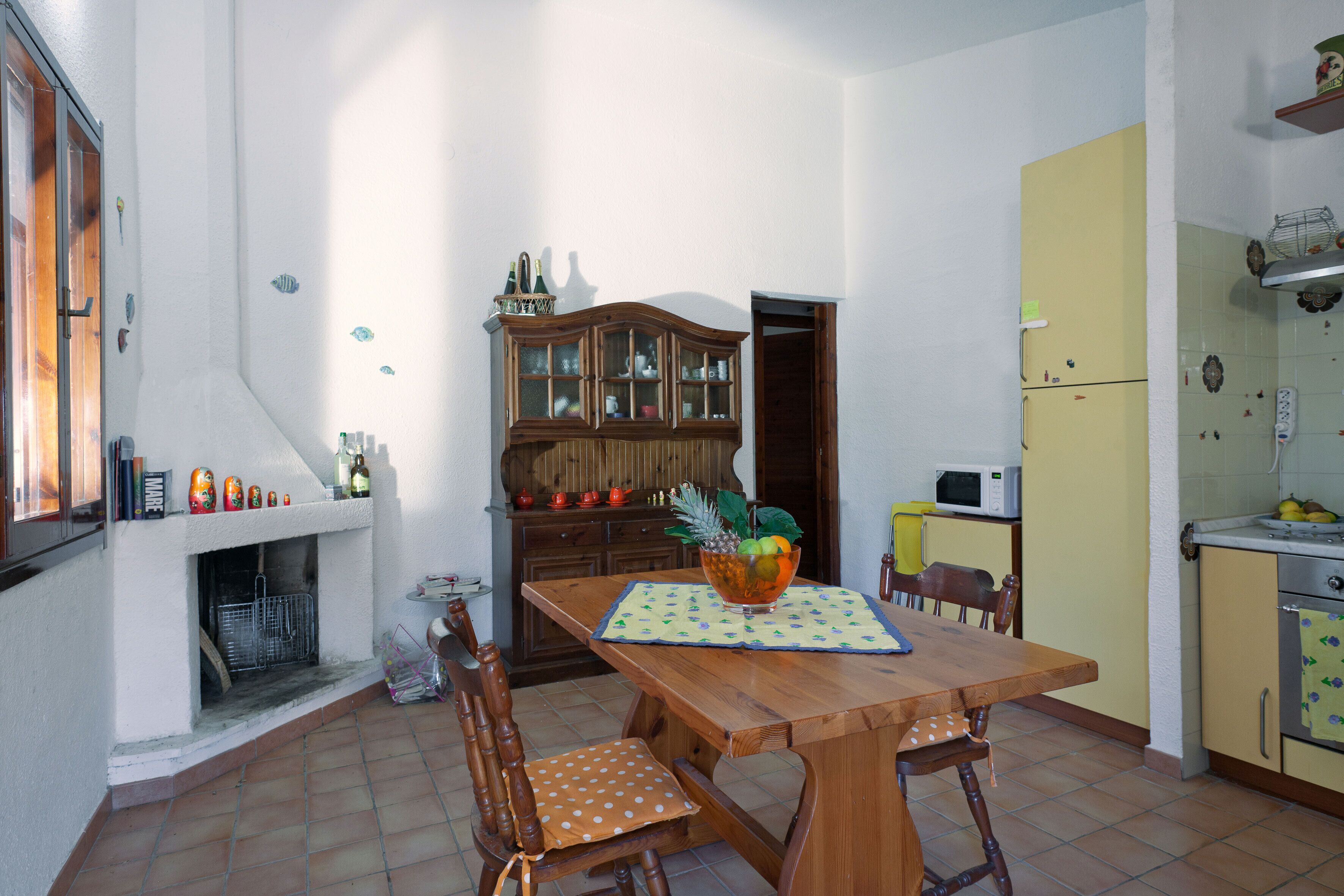Un comedor con mesa de madera, sillas, un armario y un microondas.