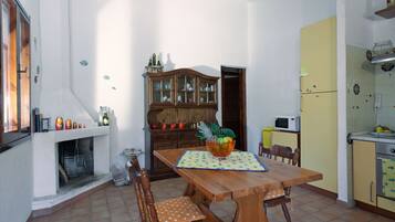 Un comedor con mesa de madera, sillas, un armario y un microondas.