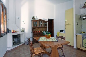 Een eetruimte met een houten tafel, stoelen, een kast en een magnetron.