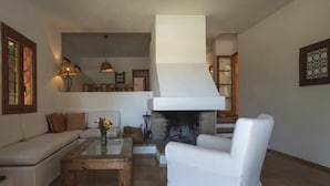 A living room with a fireplace, white furniture, and a wooden coffee table. - Cana Lúa. Charming Villa With Fantastic Sea View And Sunset (Sant Josep de sa Talaia)
