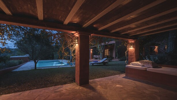 An outdoor patio area with stone flooring, a pool, and a covered seating area with cushions. - Cana Lúa. Charming Villa With Fantastic Sea View And Sunset (Sant Josep de sa Talaia)
