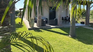 Un espace patio aménagé avec du mobilier d’extérieur, un coin salon abrité et une pelouse bien entretenue.
