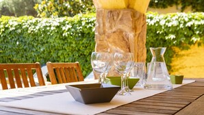 Ein Holztisch mit Tischset, zwei Stühle, einer Glas-Karaffe und mehreren Gläsern.