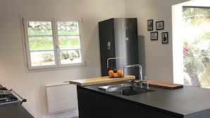 Une cuisine moderne avec un plan de travail noir, un évier encastré et une fenêtre donnant sur un paysage verdoyant.