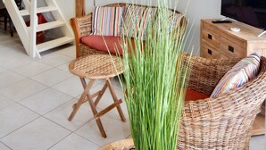 Ein Wohnzimmer mit Korbmöbeln, einem farbenfrohen Wandbild, einer Treppe und einem Fernseher.