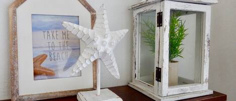 A framed picture with a beach scene and a white starfish decoration on a wooden shelf.