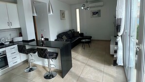 A modern kitchen with a central island, bar stools, and a dining area with a sofa and coffee table. - Modern 2 Bed Detached Villa | Private Pool | Near Quesada | Peaceful Location  (Rojales)