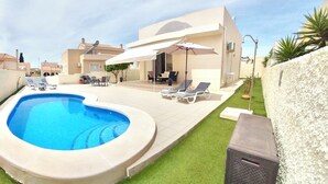 A swimming pool with lounge chairs, a covered patio, and a well-maintained lawn. - Modern 2 Bed Detached Villa | Private Pool | Near Quesada | Peaceful Location  (Rojales)