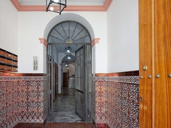 A hallway with patterned walls, a wooden door, and a staircase leading to another area. - El Rico Rincón in Sanlúcar la Mayor (22 km from Seville) (Sanlúcar la Mayor)
