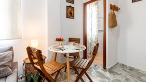Un coin repas avec une table ronde, des chaises et un saladier de fruits.