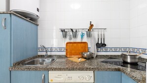 Une cuisine dotée d’un plan de travail en granit, d’un évier, d’une cuisinière et d’un lave-vaisselle.