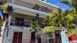 Un immeuble à plusieurs étages doté de balcons, entouré de palmiers.