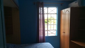 Une chambre avec un lit, une fenêtre avec des rideaux et une armoire.