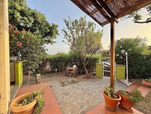 Un espacio al aire libre cubierto con suelo de piedra, plantas en macetas y una estructura de pérgola.