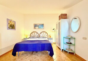 A bedroom with a bed, bedside tables, a wardrobe, a mirror, and wall art.
