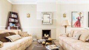 A living room with two sofas, a coffee table, a bookshelf, a fireplace, and wall-mounted lamps. - Hidden Gem on the Spanish Steps - Terrace - Great Air Conditioning (Roma)