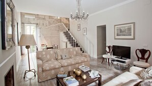 A living room with a sofa, coffee table, TV, and a staircase leading to another room. - Hidden Gem on the Spanish Steps - Terrace - Great Air Conditioning (Roma)