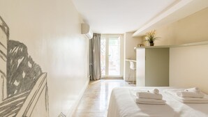 A hotel room with a bed, a desk, a chair, a potted plant, and a view through a glass door. - Hidden Gem on the Spanish Steps - Terrace - Great Air Conditioning (Roma)