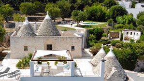 A stone building with conical roofs, a pool, and outdoor seating.
