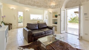 A modern living room with a leather sofa, glass coffee table, and a stone ceiling.