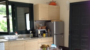 Een compacte keuken met een eethoek, inclusief een koelkast, magnetron en diverse keukengerei.
