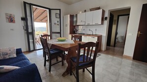 A compact living space with a dining area, kitchen, and a view through an open door. - House with independent apartment with a splendid view of the sea - Seccagrande Ribera (Ribera)