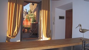 Quarto com bancada de madeira, escultura de pássaro e vista para área externa com plantas e uma cadeira.
