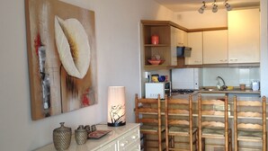 Une cuisine avec un meuble blanc, une chaise en bois et une table avec une lampe.