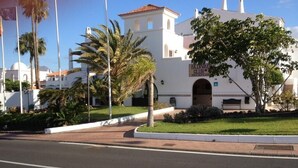 Un bâtiment blanc avec une enseigne indiquant « FALCONVILLE CLUB » et un palmier au premier plan.