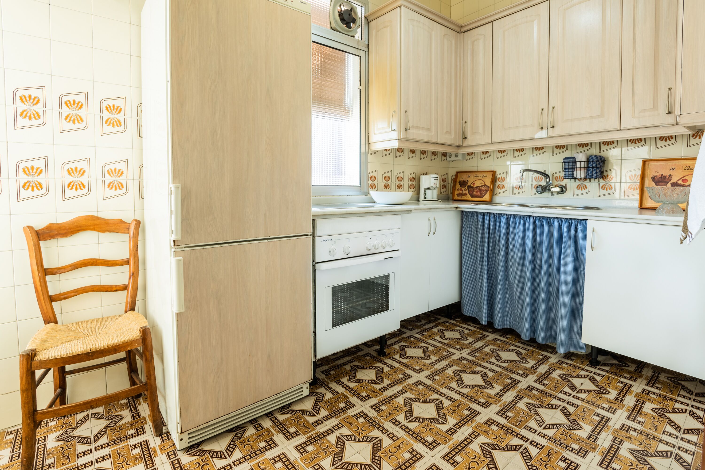 Une cuisine équipée d’un réfrigérateur, d’une cuisinière et d’une chaise en bois.