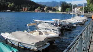 A marina with several boats docked, a clear sky, and a mountainous backdrop.