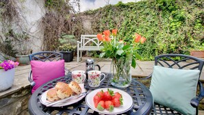 A table set outdoors with a plate of strawberries, a pitcher of flowers, and a teapot. - Barbican View, luxury Grade II listed apartment opposite Alnwick Castle (Alnwick)