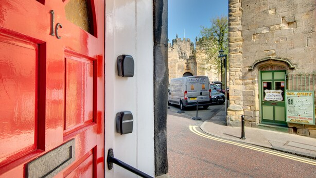 A red door with a mailbox and a green door labeled "Antiques" in the background. - Barbican View, luxury Grade II listed apartment opposite Alnwick Castle (Alnwick)