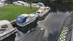 Un canale con imbarcazioni ormeggiate, una zona verde e un ponte.