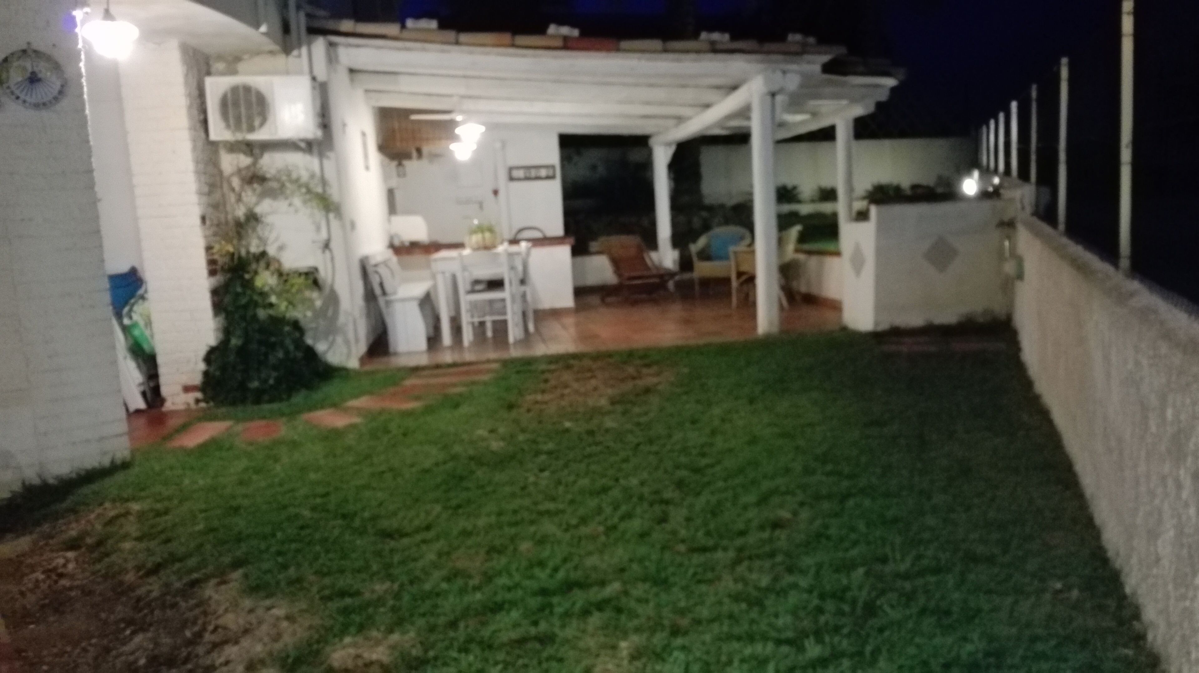 Een overdekte patio met gras, een tafel en stoelen.