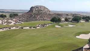 Un campo de golf con búnkeres de arena, una gran formación rocosa y árboles.