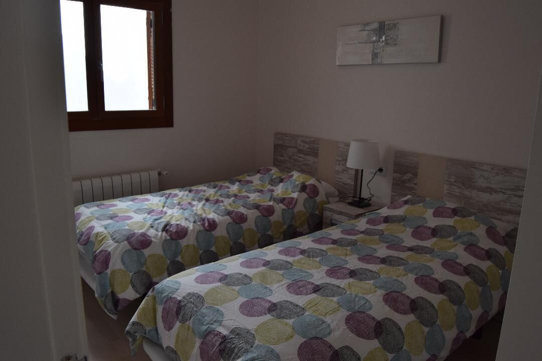 A room with two beds, each with a polka dot bedspread, a bedside lamp, and a framed picture on the wall.