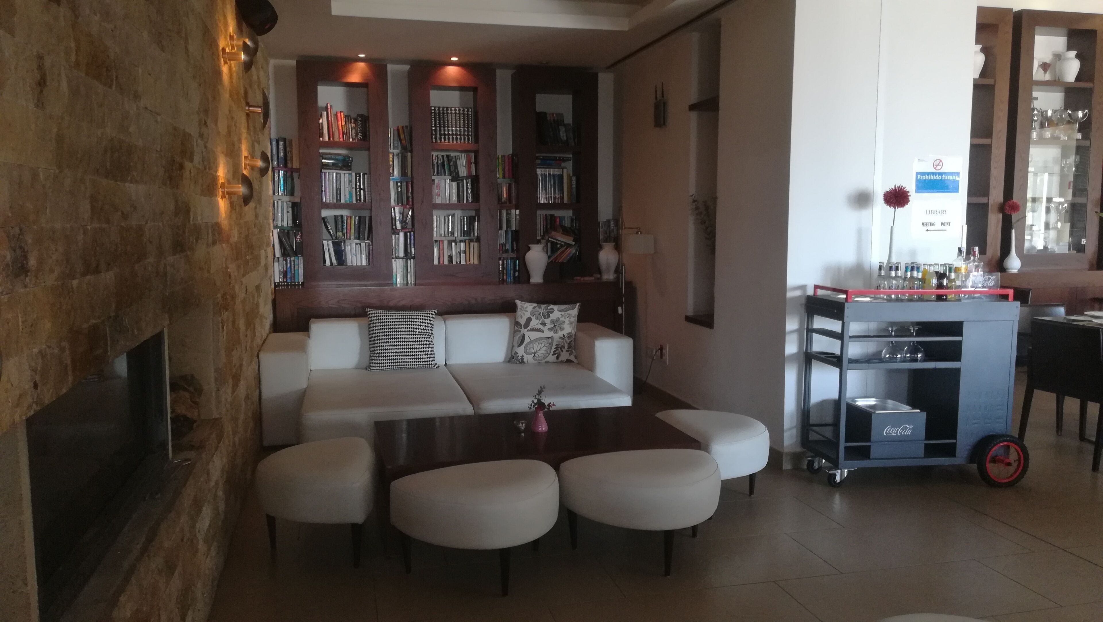 A modern living room with a sofa, ottomans, a coffee table, and a bookshelf filled with books.