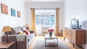 A living room with a sofa, coffee table, TV, and a window with curtains. - Casa da Avenida III Lisboa (Lisbon)