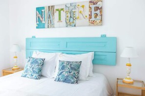 A bed with a turquoise headboard, white bedding, and two decorative pillows.